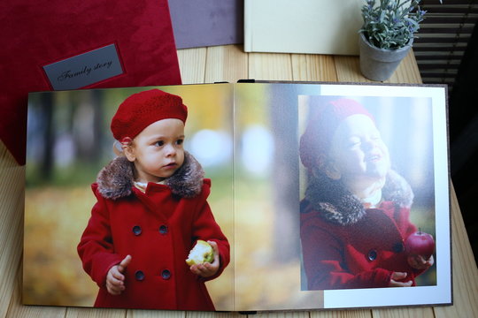 Photo book printed where a little girl in a red coat and beret. Albums, memory, family values. Printed products concept.