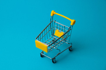 Trolley for shopping on a blue background. Supermarket food price concept, holiday discounts