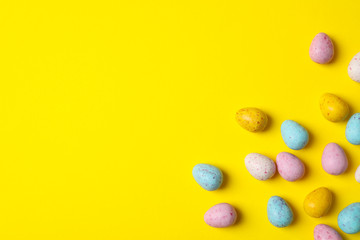 Fototapeta na wymiar Small Easter eggs on yellow background, space for text