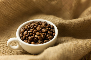 Fototapeta premium A scattering of coffee beans with a cup of coffee.