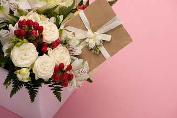 bouquet of flowers in festive gift box with greeting card on pink background
