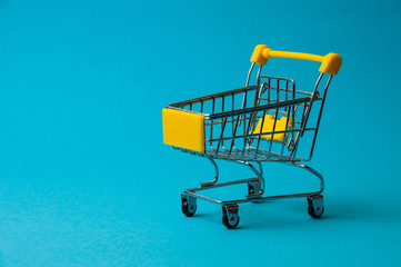 Trolley for shopping on a blue background. Supermarket food price concept, holiday discounts