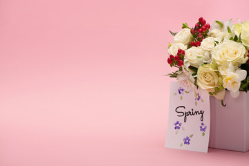 bouquet of flowers in festive gift box with spring greeting card on pink background