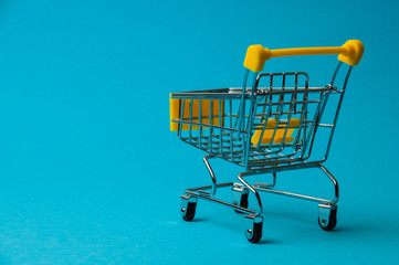 Trolley for shopping on a blue background. Supermarket food price concept, holiday discounts