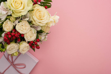 top view of bouquet of flowers in festive gift box with bow on pink background