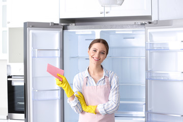 Fototapeta na wymiar Woman with rag near clean refrigerator at home
