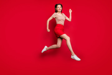 Full body profile photo of pretty lady jump high rejoicing rushing summer final season sale prices shopper wear casual striped t-shirt red skirt isolated red bright color background