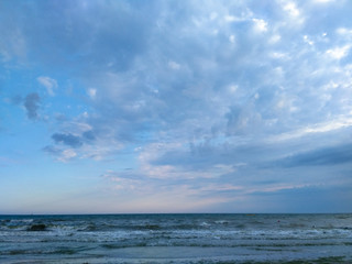 Blue clouds over the waves of the sea