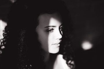 beautiful curly girl posing on camera, black and white, hard sun light