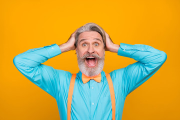 Closeup photo of cool clothes crazy white haired grandpa open mouth see sale shopping advert arms on head wear blue shirt suspenders bow tie isolated yellow color background