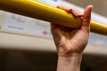 closeup woman hand holding handrail (grip) inside a train in London. Virus hygiene and safety.