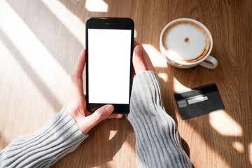 Mockup picture of business woman’s hands holding smart phone with white blank screen in modern place