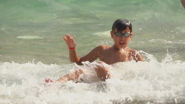 High waves of the sea surf cover boy in a swimming goggles. Waves breaking and splashing
