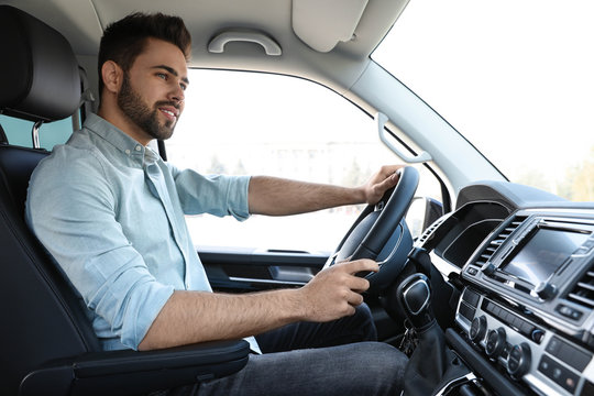 Handsome young man driving his modern car