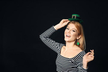 Young woman with green leprechaun hat on black background, space for text. St. Patrick's Day...