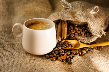 Coffee cup with cinnamon sticks and coffee bag on wooden table