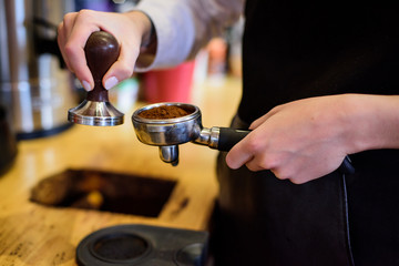 Fototapeta na wymiar Hand of barista holding coffee machine holder filled with coffee