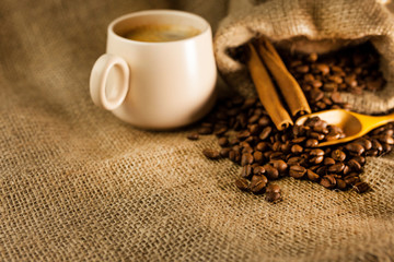 Coffee cup with cinnamon sticks and coffee bag on wooden table