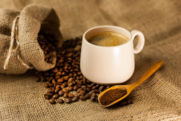 Coffee cup with cinnamon sticks and coffee bag on wooden table