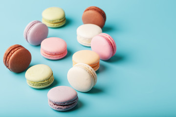 Macaroni cookies of different colors are scattered on a blue background.