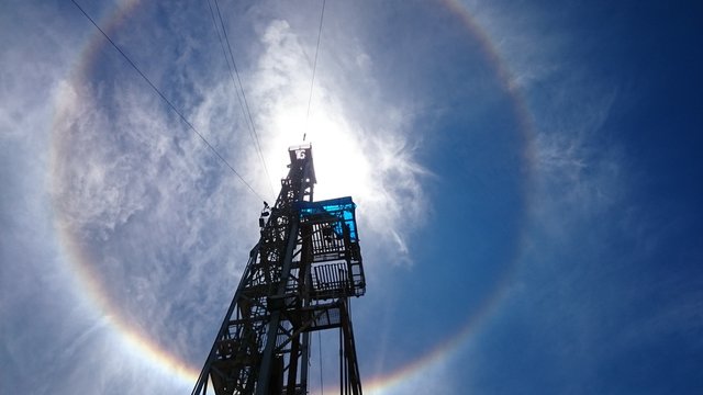 A picture of sun is taken beneath from a oil rig tower.