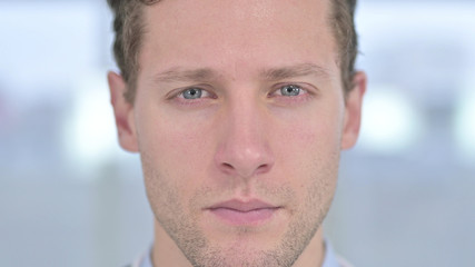 Obraz premium Close up of Face of Serious Young Male Looking at Camera