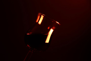 Studio photography of isolated shiny tulip liquor sherry glass illuminated by red light (Focus on glass rim left)