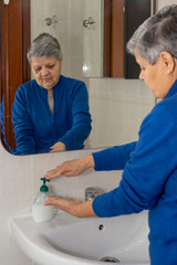 Obraz premium Old lady washing her hands properly to avoid contagious illnesses like the flu, colds.