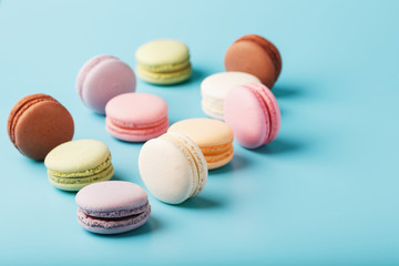 Macaroni cookies of different colors are scattered on a blue background.