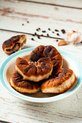 Belyashi or tasty homemade fried dough with minced meat. Pies are on a white and blue plate on a wooden table. Black peppercorns and garlic background. Copy space. Vertical orientation