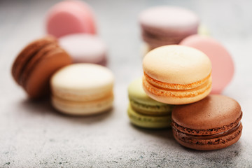 Multicolored macaroni cookies lie on a gray stone slab.