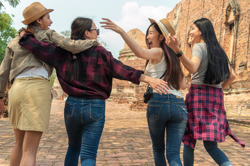 Back side of four young female travelers are walking and laughing.