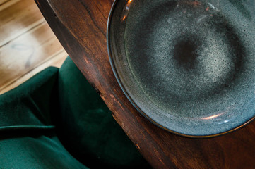 Abstract view of beautiful plate on a wooden table next to a green designer chair