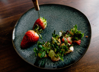 Strawberries half eaten on plate on wooden table