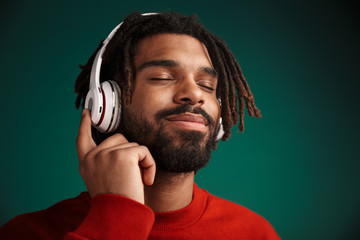 Portrait of pleased african american man smiling and using headphones