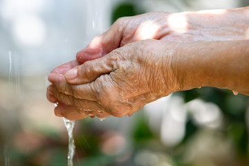 Senior woman washing her hands in bokeh green garden background, Close up & Macro shot, Selective focus, Prevention from covid19, Bacteria, Healthcare concept