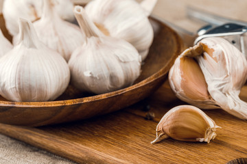 garlic cloves in wooden plate on burlap background