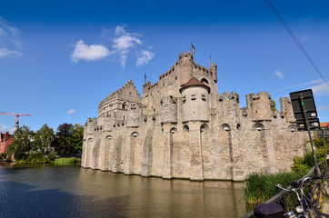 Fototapeta na wymiar Ghent, Belgium, August 2019. The Gravensteen is the castle of the counts of Flanders. View from the side of the moat: the imposing medieval structure. Sunny day.