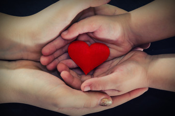 adult and child hands holding red heart, health care, donate and family insurance concept,world heart day, world health day, CSR concept, adoption foster family.Image is tinted