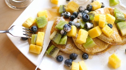 Having Vegan Pancakes With Berries, Fruits And Peanut Butter And Drinking Coffee Latte. 