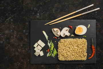 Chinese instant noodles with mushrooms, egg, tofu cheese, chopsticks dark background. Asian food.