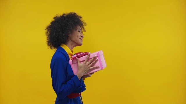 surprised african american girl taking present isolated on yellow