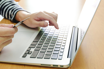 Men hand holding credit card and type payment information on keyboard for order online shopping. Internet technology and Digital market place E-Commerce lifestyle concept, Purchase transaction.