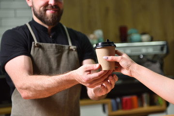 The bartender gives the customer coffee in a paper Cup, hands close-up. Small business, people and service concept