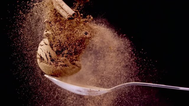 A Full Spoon Of exotic Christmas spice cinnamon anise and nutmeg falling down  on black background closeup in super slow motion