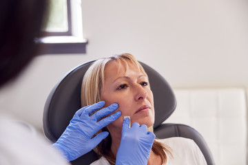 Mature Woman Sitting In Chair Being Give Anti Ageing  Injection By Female Doctor