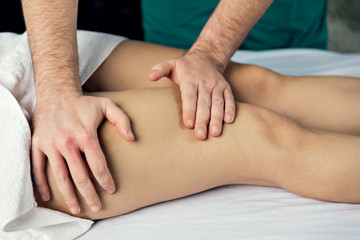 Lymphatic drainage massage of the hips. Man's hands.