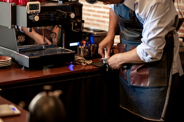 The barista with blue shirt making coffee with a espresso machine.