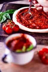 Adding pizza tomato sauce on the raw dough. Italian pizza preparation.