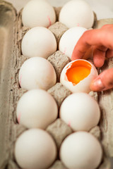 Holding a broken white egg in a cardboard box